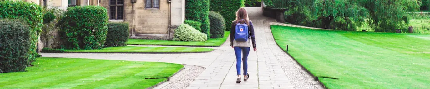 Back of a college student with a book bag walking next to a school building, greening your dorm is the new thing